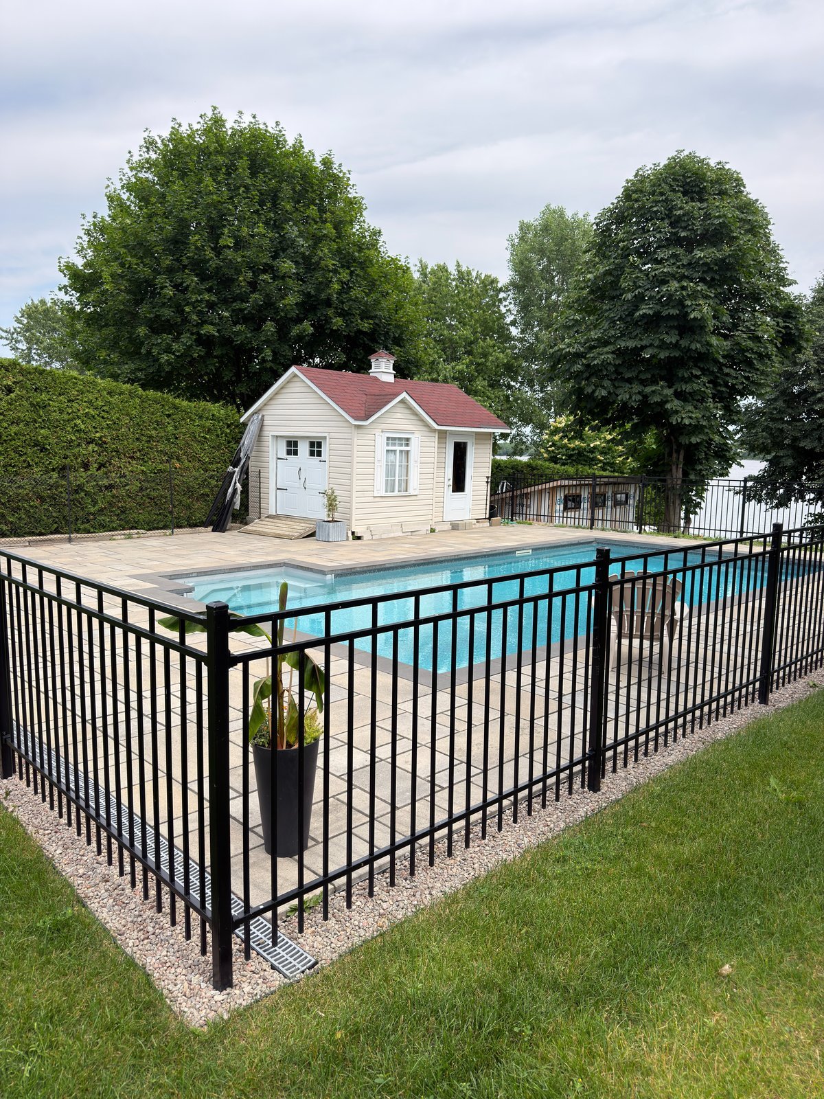 Clôture ornementale en aluminium noir entourant une piscine creusée avec spa intégré